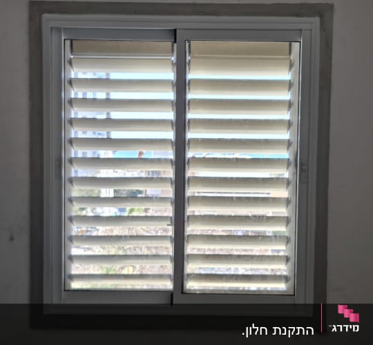 חלון עם תריסי אלומיניום בחדר